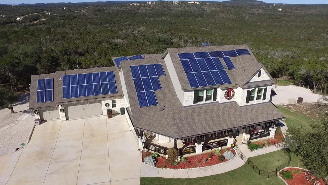 An aerial view of a Hill Country home with a rooftop solar array